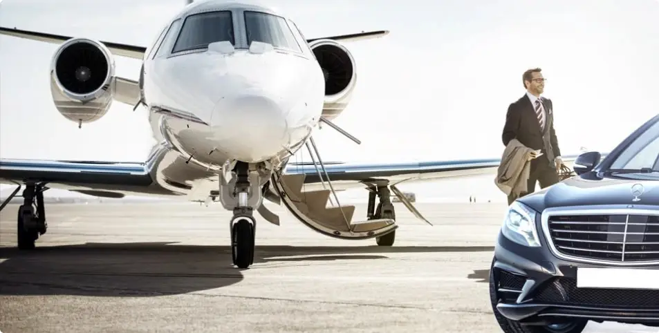 Businessman walking on an airport tarmac near a private jet and luxury car.